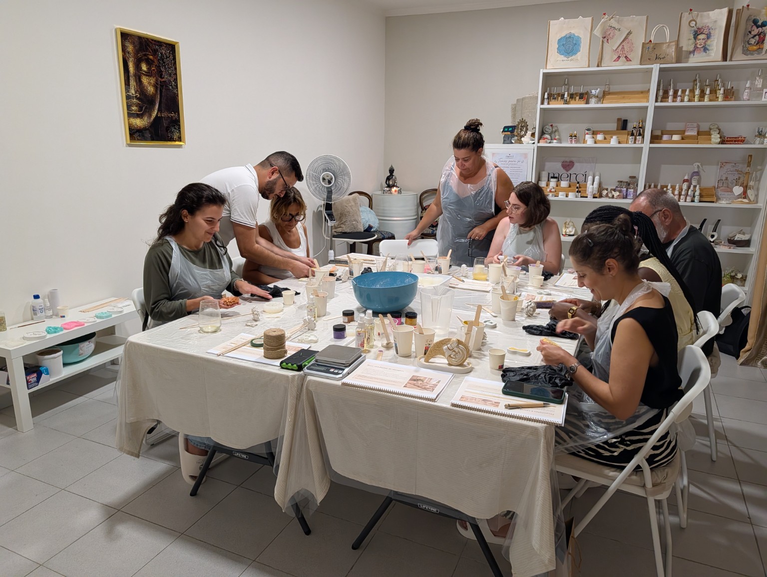 Participantes de um workshop Merci em volta da mesa, a moldar as suas peças artesanais
